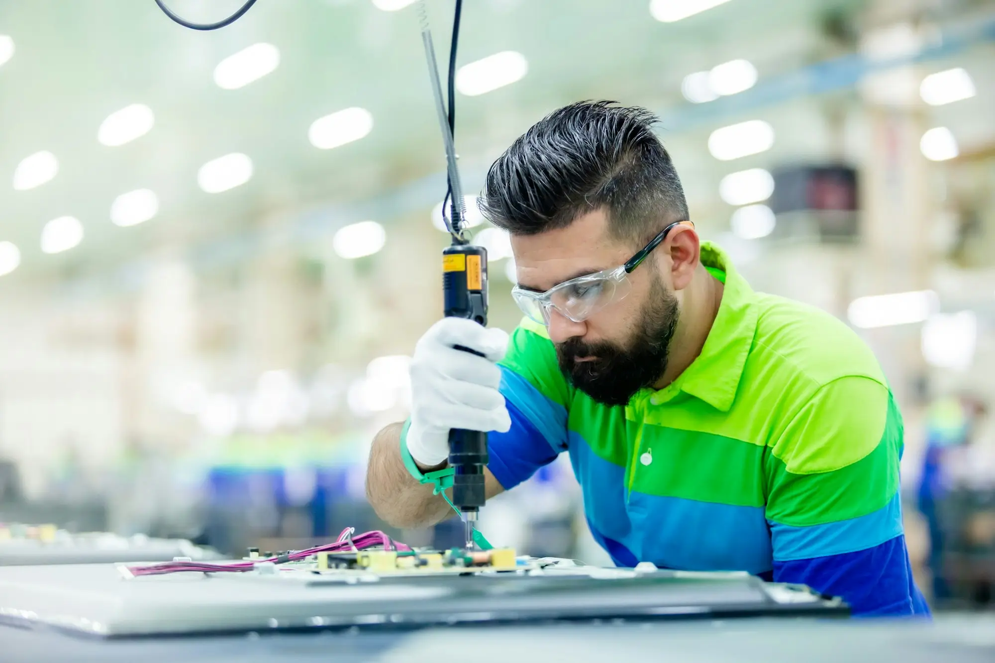 Technician repairing electronics on a factory bench