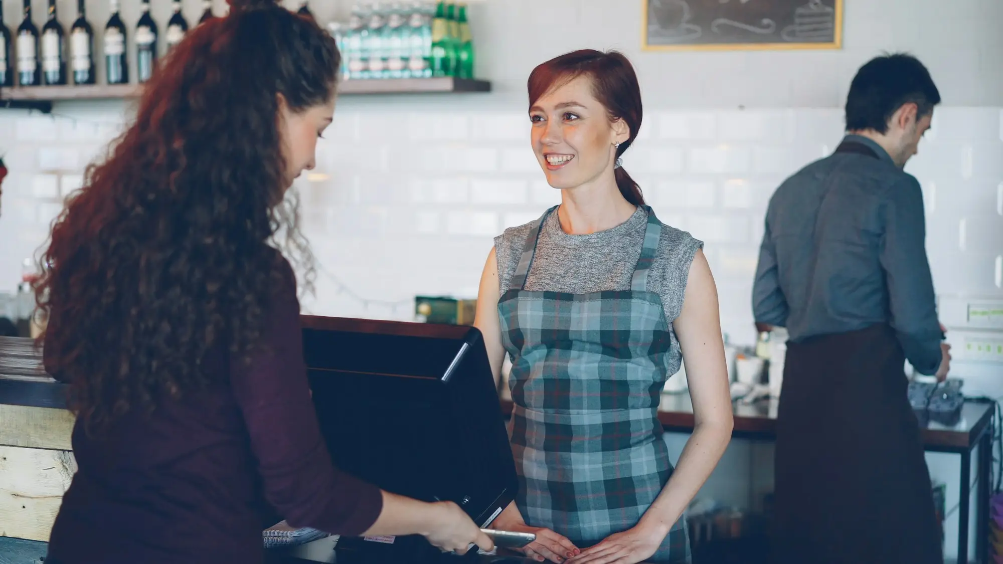 Shop owner taking a call at the counter with customers