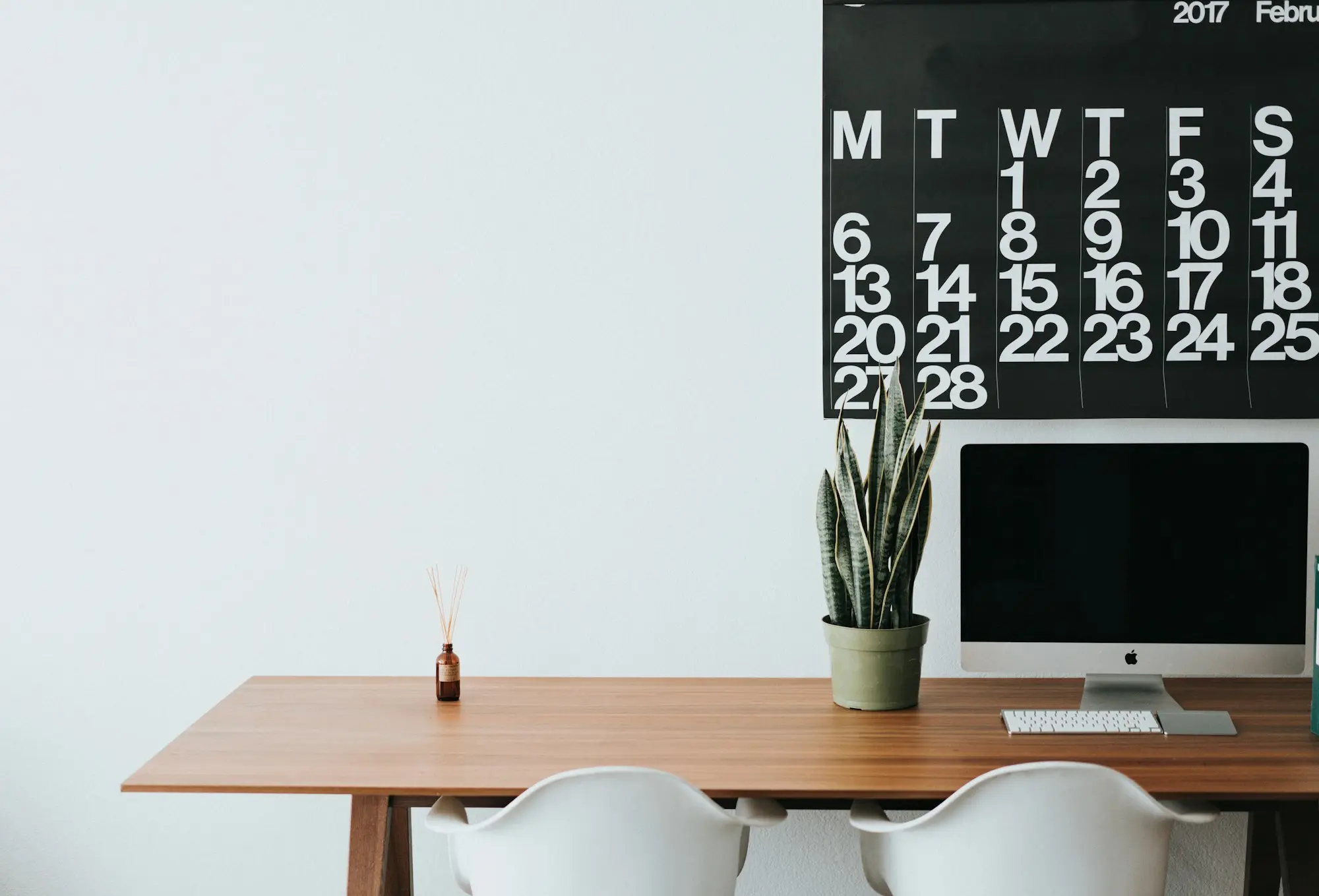 Wall calendar above a tidy desk for planning bill due dates